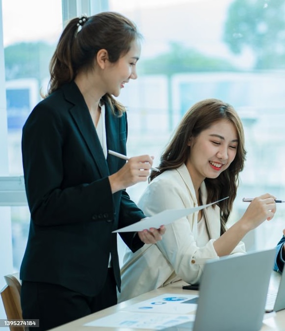 Hai đồng nghiệp trao đổi nghiệp vụ bên bàn làm việc